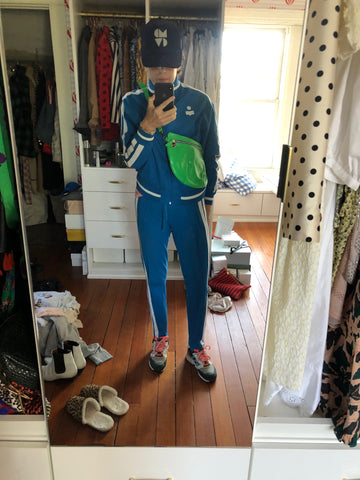 Clare Vivier Taking A Selfie In Front of A Mirror, Wearing A Blue Tracksuit and Our Neon Green Grande Fanny