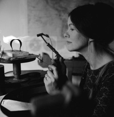 A black and white photo of Vivianna Torun Bülow-Hübe working at her jewelers bench with a blowtorch