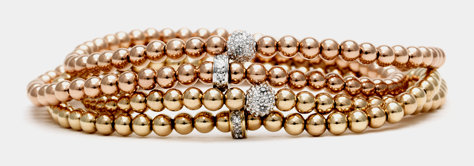 Rose gold beaded bracelets with sparkling diamond accents on a white surface.