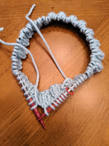 Photo of the beginning of a hat on a 16" needle in white bulky yarn.