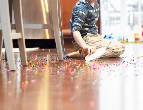kid sitting down on a floor with spilled beads