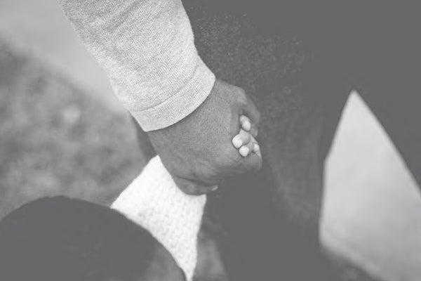 close up of Father and infant son holding hands