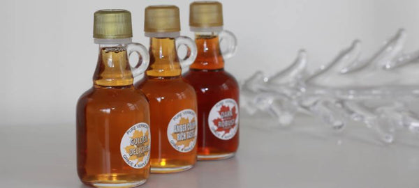 three glass bottles of bread loaf view farm maple syrup on white background with glass tree