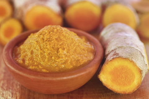 Raw tumeric paste in a bowl on a wooden surface
