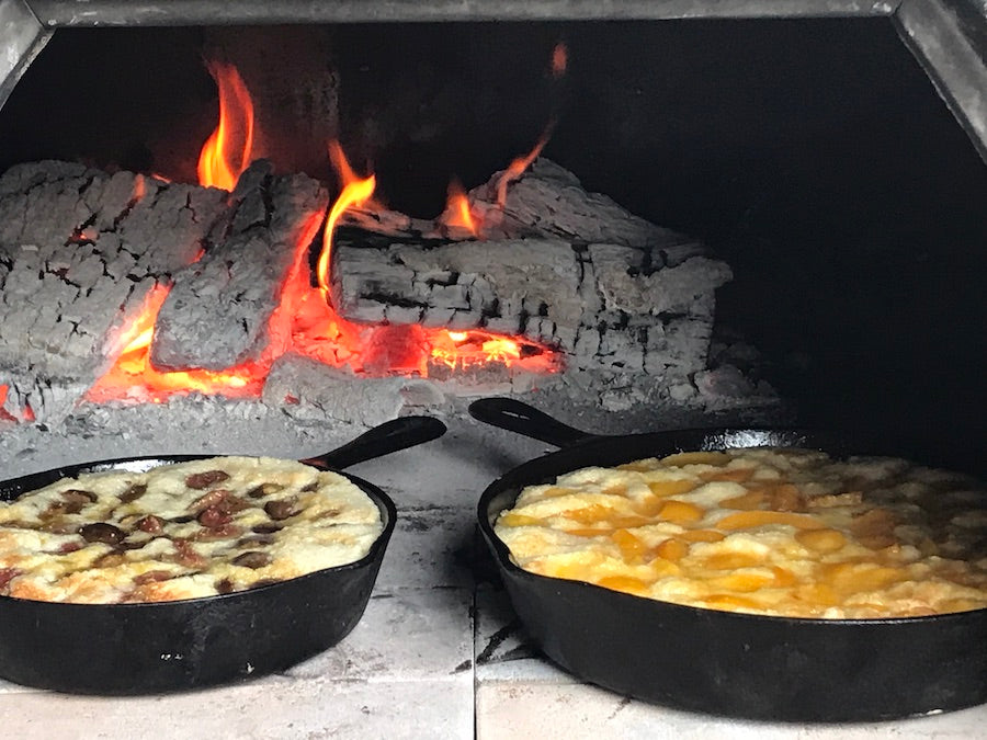 Peach and fig cobbler baked in cast iron skillets inside a wood fired pizza oven