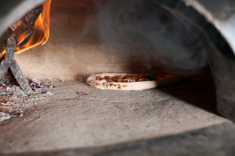 Pizza cooking in a smoky brick oven