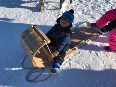 child on wooden toboggan sled