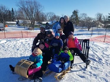 family with wooden toboggan sled and wooden sled