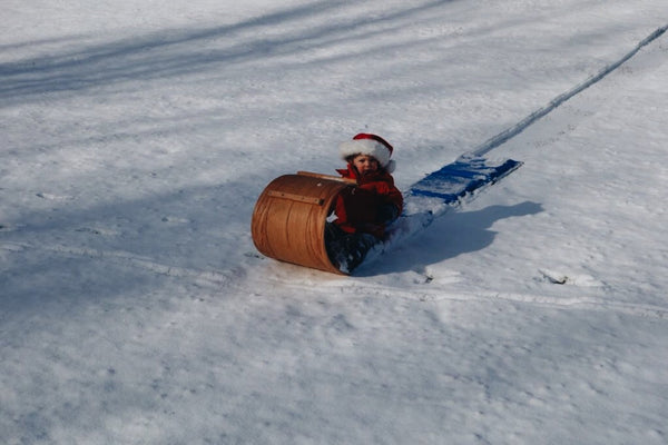 Small boy in a santa hat, sitting on snowy toboggan sled