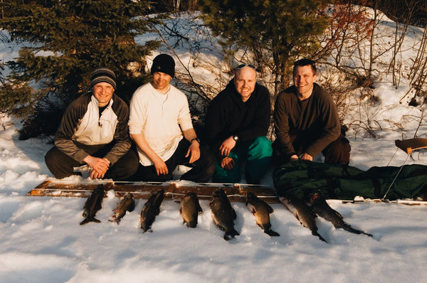 Eight Lake trout laied out in the snow beside a wooden hand toboggan 