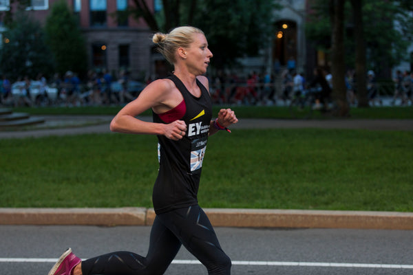 A female triathlete is running on the track.