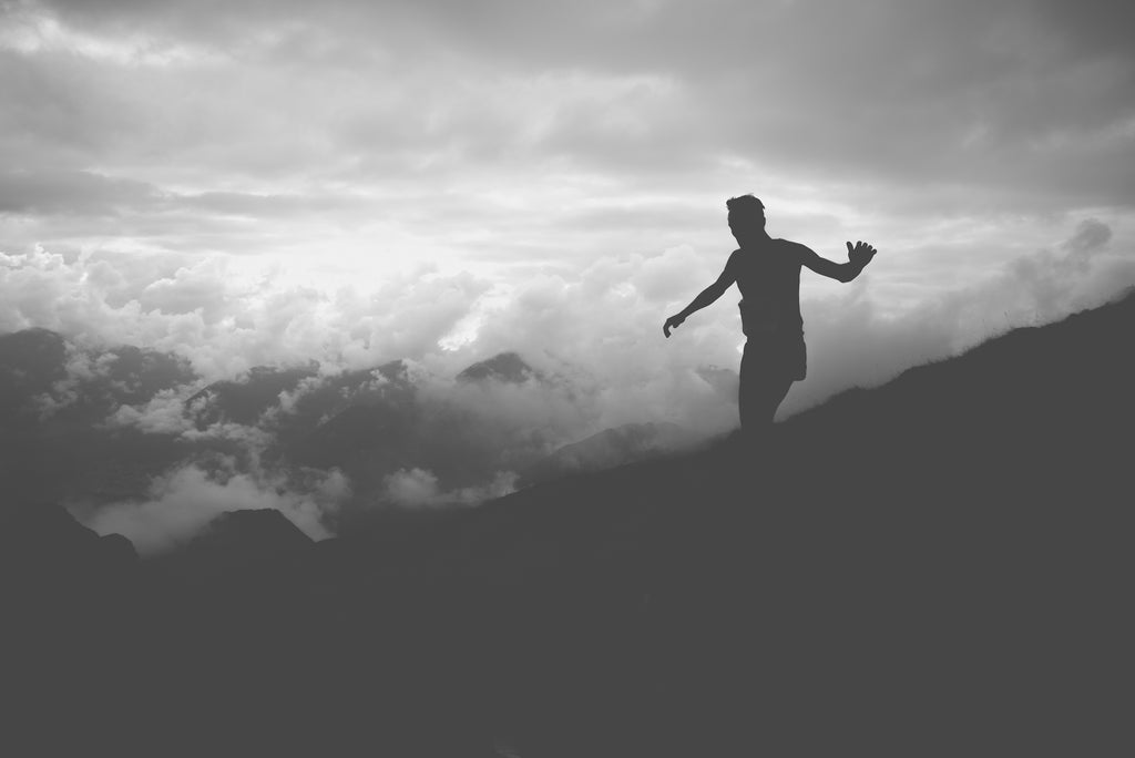 A black and white image of a fell runner running down the mountain in misty weather.
