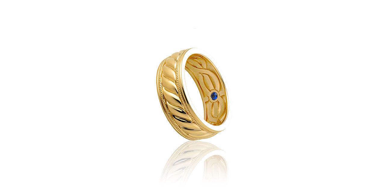 A photograph of a yellow gold mens wedding band with a cord of three strands design on the inside and outside.