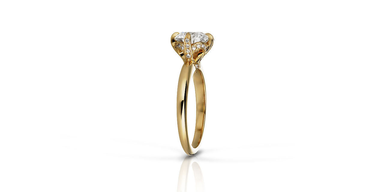A photograph of the side of a yellow gold solitaire engagement ring with diamond set prongs
