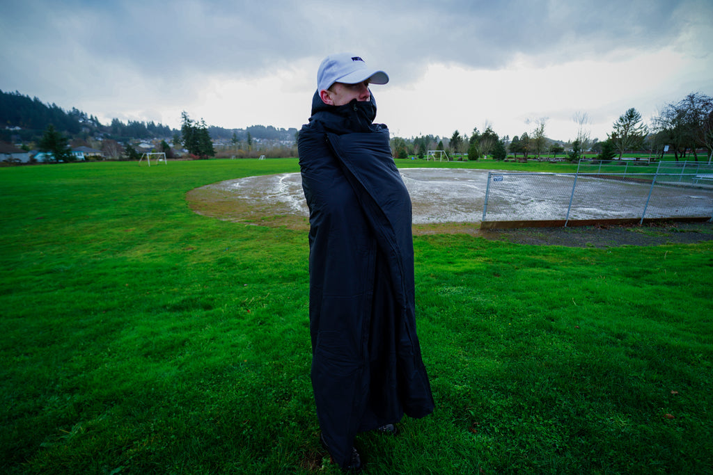 Rainy day at a baseball game. Baseball player wrapped up in a Wallrest