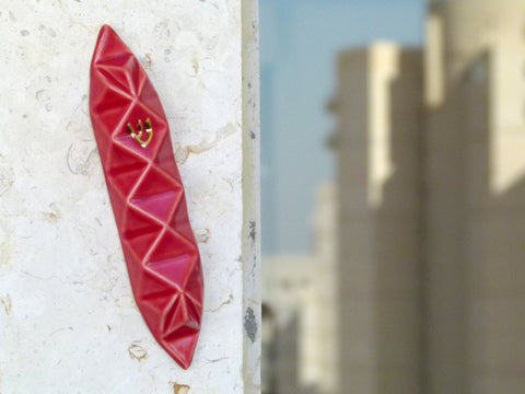 Mezuzah case, red ceramic, origami style, on a doorpost in a modern Jewish apartment