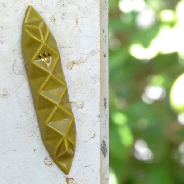 A Mezuzah case in olive green glaze, at Yael's home, reflecting her blooming mediterranean garden.