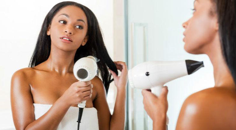 blow drying hair in front of mirror
