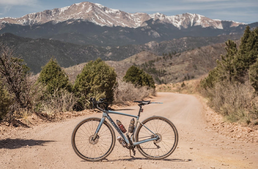 Gravel bike on dirt road with snow capped peaks in the distance