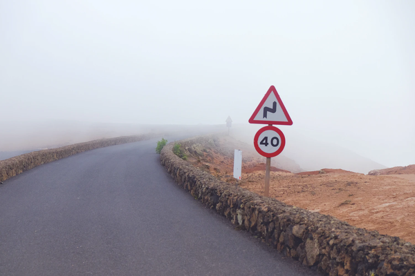 Road with fog and 40 miles per hour sign and tight bend warning