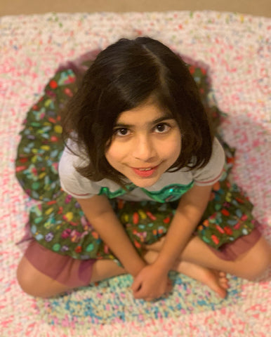 A girl sitting on a pastel pink toothbrush rug