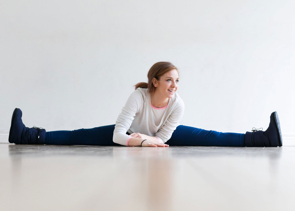girl on floor at home doing splits and smiling
