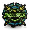 The back of Fire Department Coffee's Shellback Challenge Coin featuring two tridents and the text "Shellback" in green.