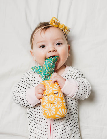 Baby chewing on a pineapple shaped rattle