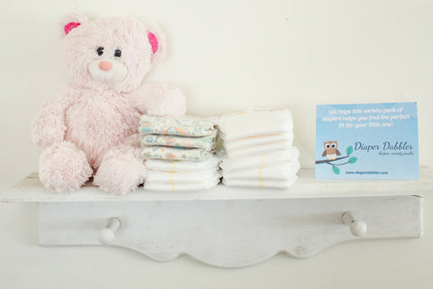 Multiple brands of diapers on a shelf with teddy bear