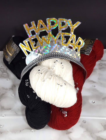 a red, white, and black skein of yarn topped with a new year tiara and a sprinkling of rhinestones