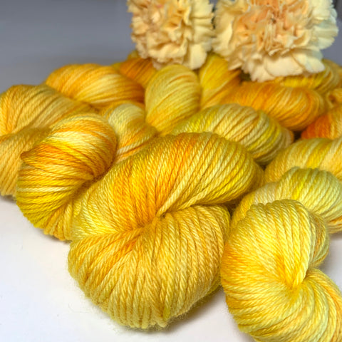 four skeins of yellow tonal yarn topped with yellow chrysanthemums 
