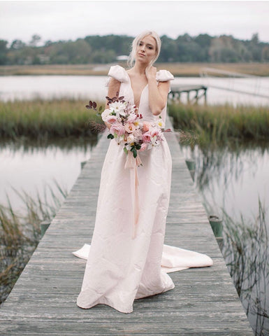 Bride on a dock surrounded by water and reeds, holding a bouquet with silk ribbon by The Lesser Bear Photo by Jenny Haas and Florals by Passiflora Studio