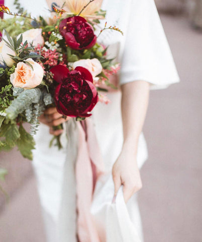 Bride holding red and pink bouquet with silk ribbon by The Lesser Bear Photo by Chad di Blasio