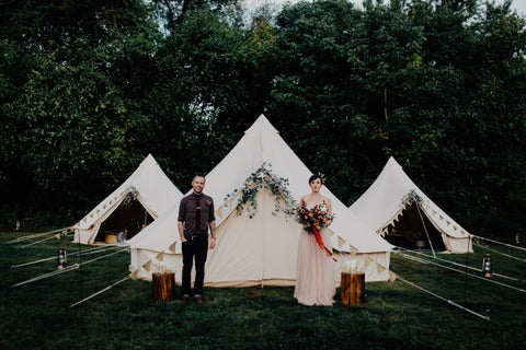 Bride and groom in front of three tents Photo by Addison Jones, Florals Bear Roots Floral and Custom Red Ribbon by The Lesser Bear