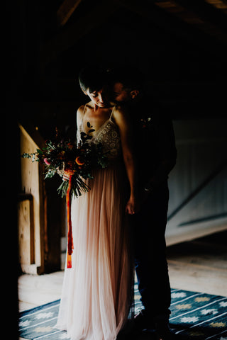 Bride and Groom in dramatic light inside barn photo by Addison Jones Florals by Bear Roots Floral and Red Ribbon by The Lesser Bear