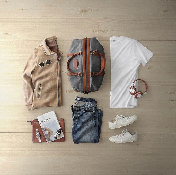 flatlay of waxed canvas weekender and leather laptop sleeve