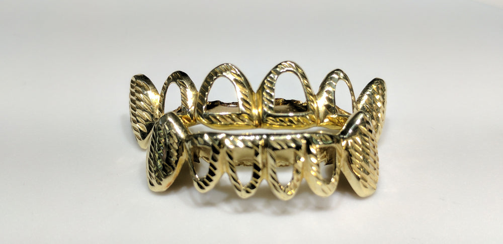 In the center: two sets of bottom and top custom made open face fang grills in 10 karat yellow gold with diamond cut finish made by Popular Jewelry in New York
