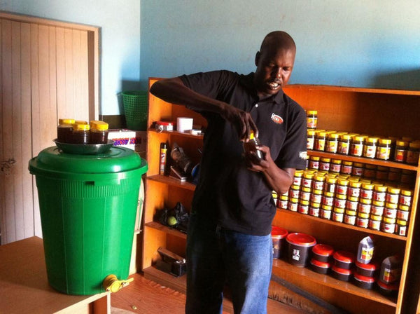 Ojok Simon holding honey made from his beekeeping project in Uganda wide
