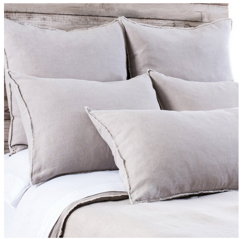 Taupe linen bedding on a bed with frayed edges