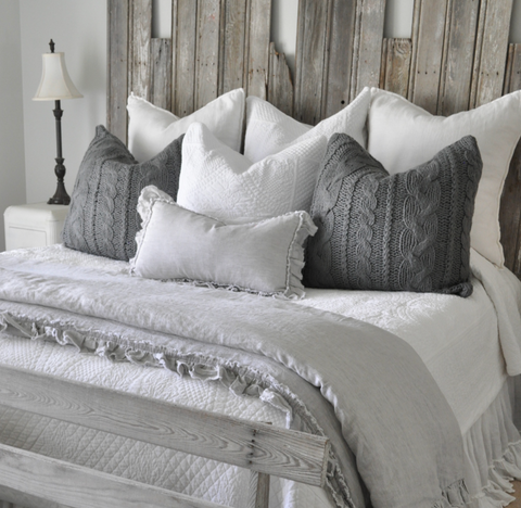 Grey bedding on a bed with a wooden headboard