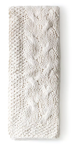 A folded white blanket knit like a cozy sweater