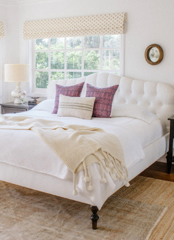 A white bed with a cream knit throw