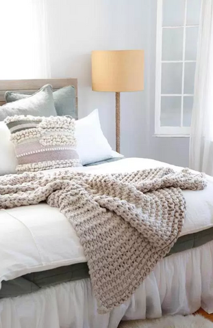 A chunky knit throw draped on a bed