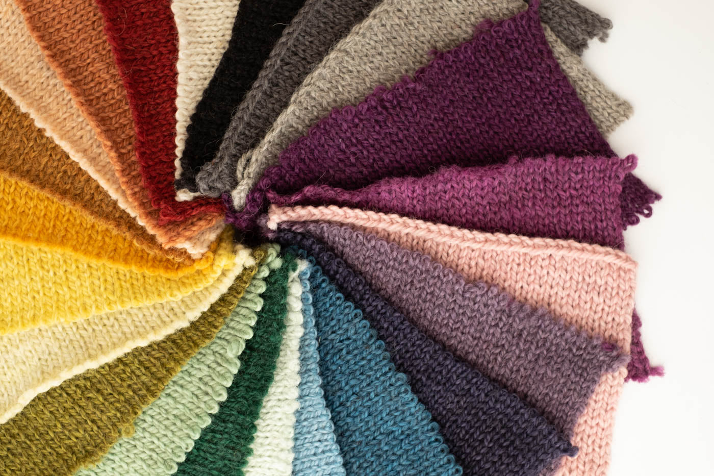 Knitted rectangular color swatches in the colors of the rainbow all in a circle.  Up close photograph of the colors.
