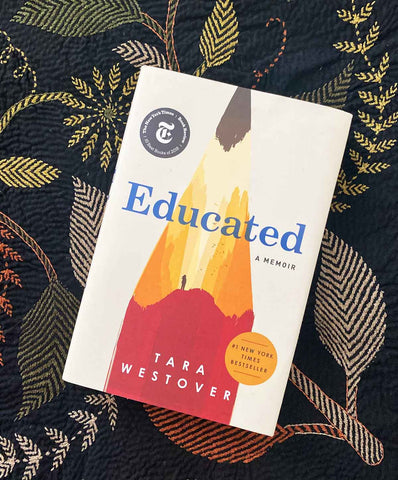 Educated by Tara Westover against a patterned throw