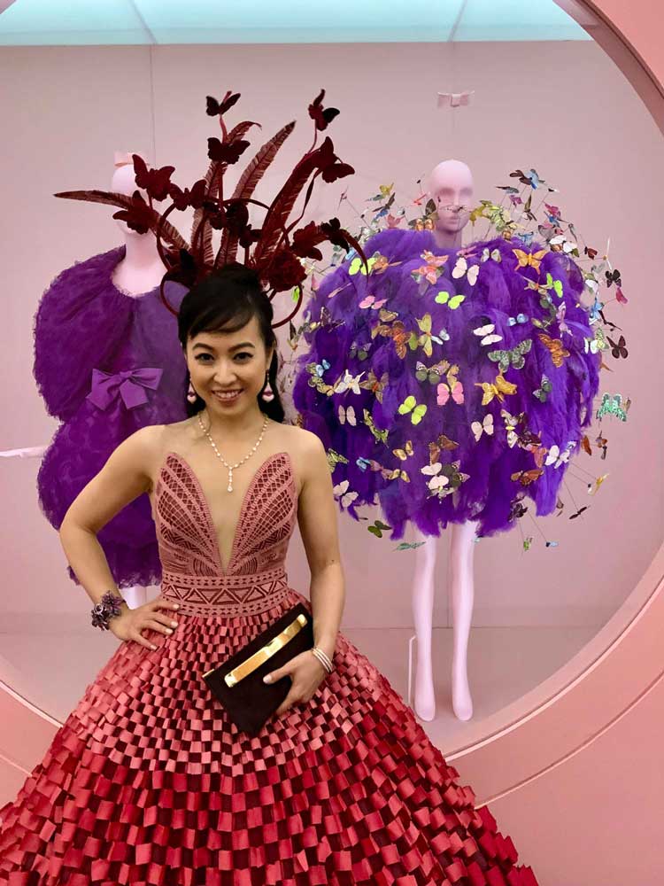 Coral posing in front of exhibit with purple dress