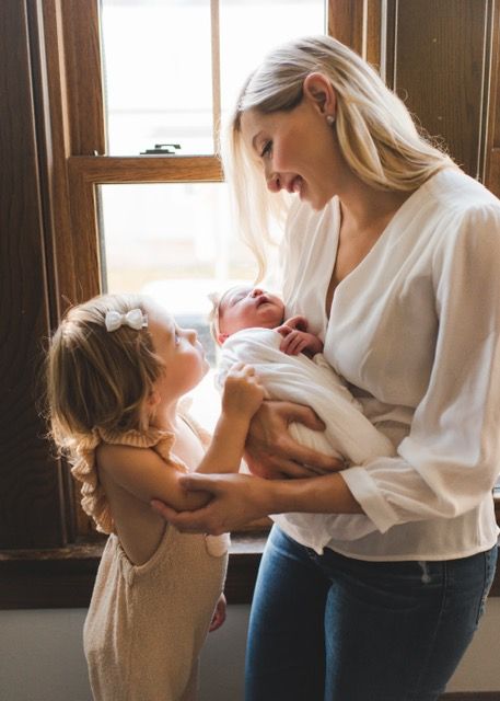 Lauren posing with her two daughters by a window