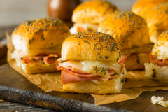 Ham and cheese slider sandwiches with black seeds sitting on top of a plate