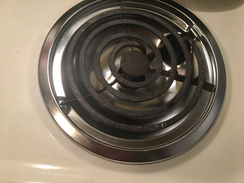 Almond color range close up of electric coil burner with shiny, new drip bowl installed below.
