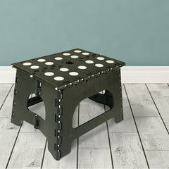 Unfolded black step stoop with white dots on top step set on a cream colored floor with teal background wall color.